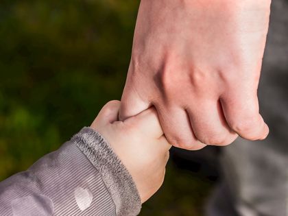 adult holding child's hand